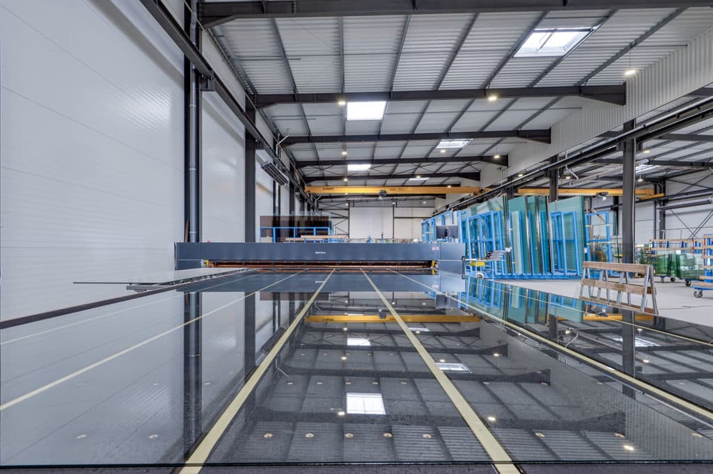 Vue panoramique de l'atelier VERTIGE à Vaulx-en-Velin — table de découpe sur sol poli, structure métallique apparente